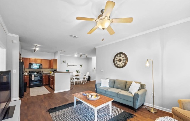 a living room with a couch and a coffee table in front of a kitchen with a stove