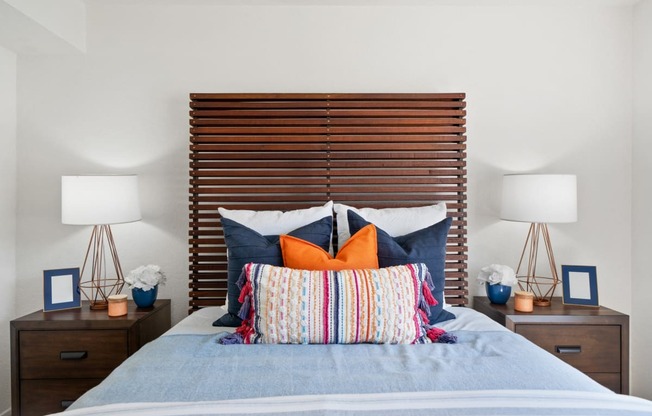 a bedroom with a bed with pillows and a wooden headboard