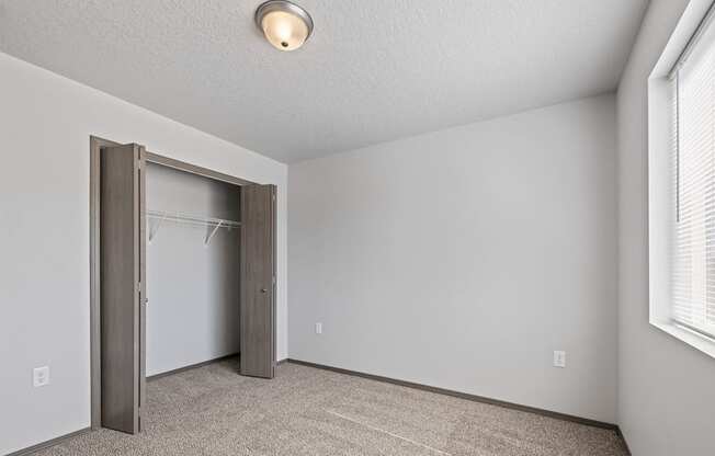 Bright, vacant bedroom with neutral walls and carpet flooring.