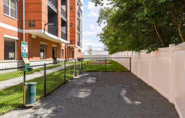 a fenced in area with a tennis court in front of a building