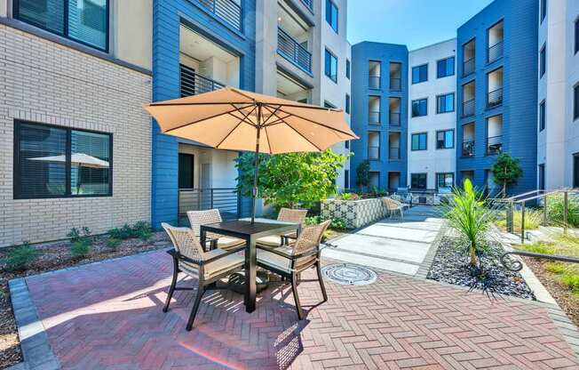 A patio with a table and chairs under an umbrella.