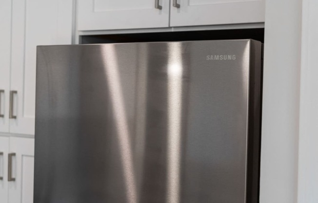 a stainless steel refrigerator in a kitchen with white cabinets