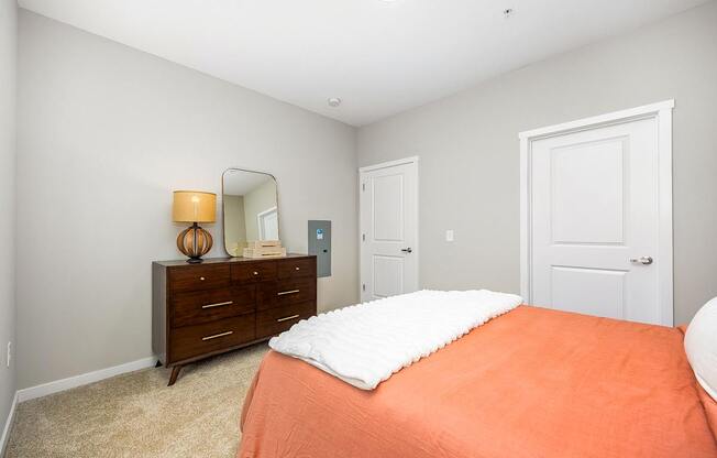 A bedroom with a bed, dresser, and mirror.