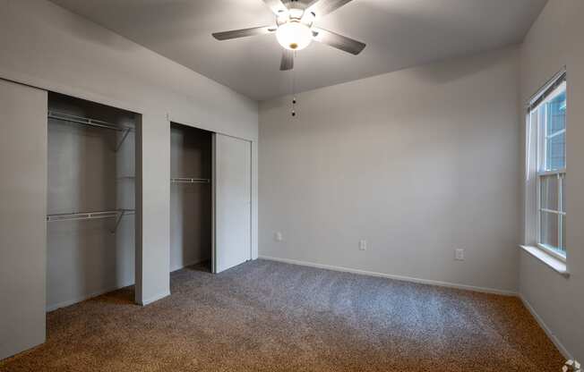 A room with a ceiling fan and carpeted floor.