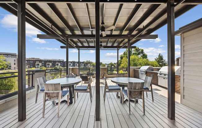 A wooden deck with a table and chairs under a roof.
