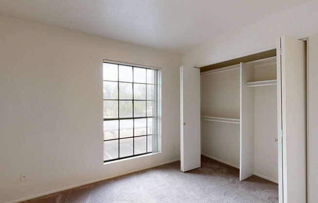a bedroom with a large window and two closets