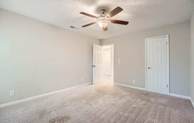 an empty living room with a ceiling fan