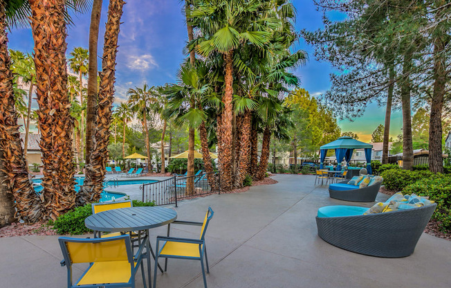 A patio with a table and chairs overlooking a pool.