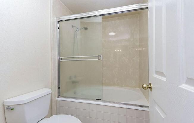 A white toilet sits next to a glass shower door in a bathroom.