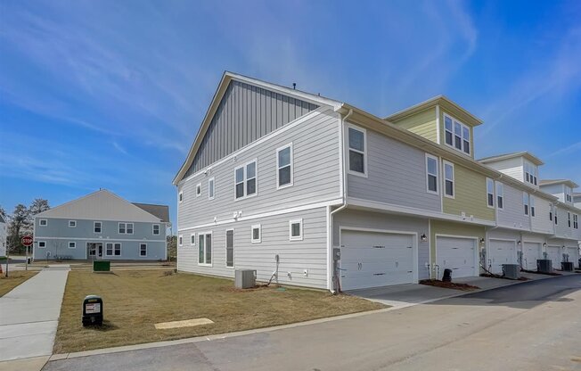A row of houses with garages and a clear blue sky.