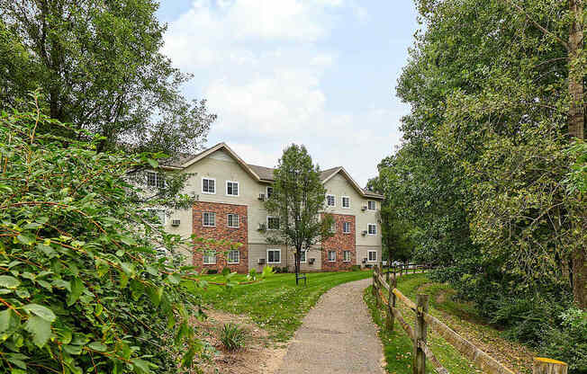 A pathway leads to a large house surrounded by greenery.