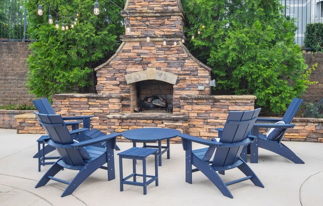 A set of blue chairs and tables are arranged around a brick fireplace.