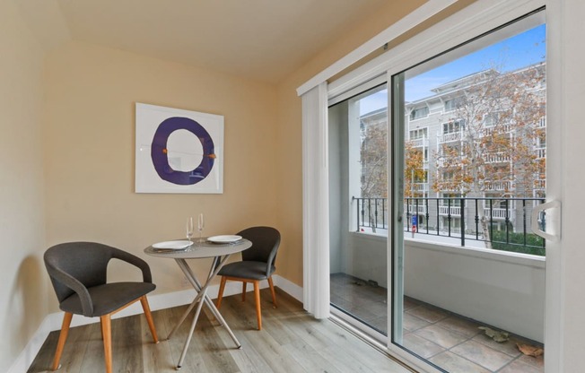 a room with a table and two chairs next to a large window