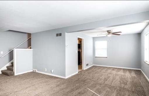 an empty room with white walls and a ceiling fan