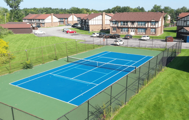 an aerial view of a tennis court with apartments in the background