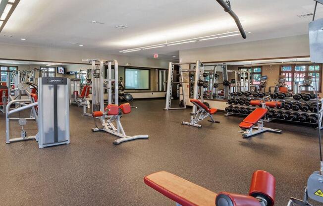 A gym with a variety of equipment including a bench, weights, and a squat rack at Vermella Lyndhurst apartments, Lyndhurst, NJ, 07071