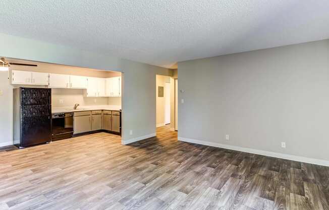 an empty living room with a kitchen in the background  at ReNew at Neill Lake, Eden Prairie