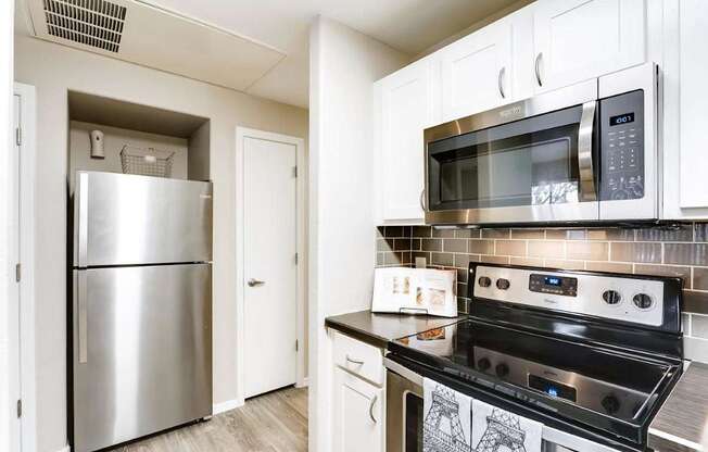 A kitchen with a stainless steel refrigerator, microwave, and oven.