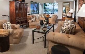 A living room with a glass coffee table and a large window.