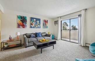 A living room with a grey couch, a coffee table, and two paintings on the wall.