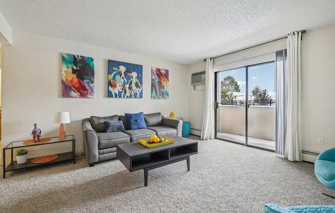 A living room with a grey couch, a coffee table, and two paintings on the wall.