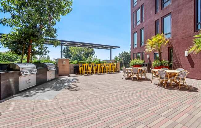 a patio with tables and chairs and a barbecue grill