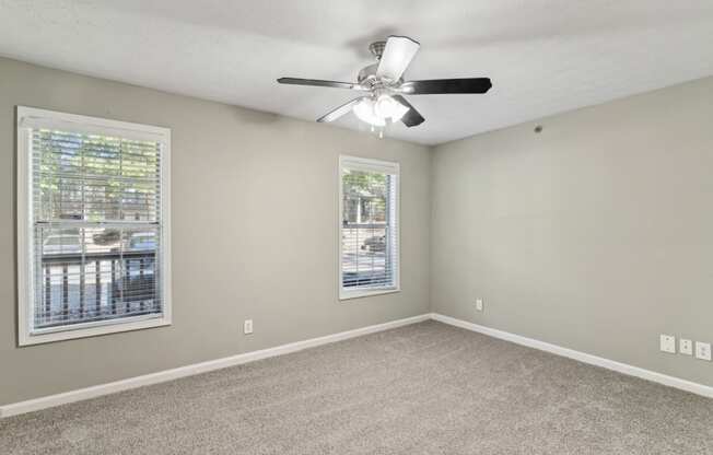 Unfurnished bedroom with plush carpeting, a ceiling fan, and windows at Oakley Run apartments in Smyrna, GA