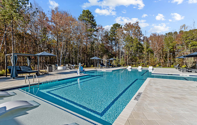 A large swimming pool surrounded by trees and a wooden deck.
