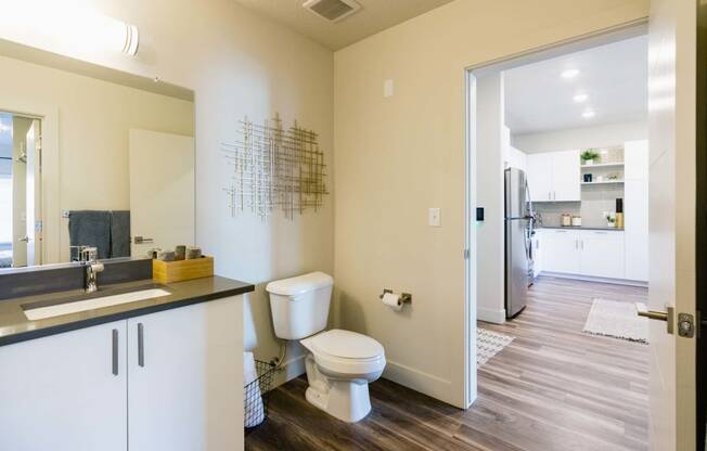 a bathroom with a toilet and a sink and a refrigerator