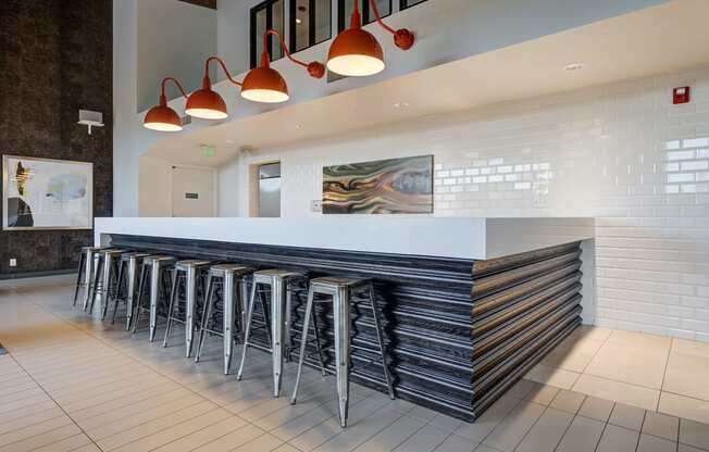 a long bar with stools in front of a white counter in a hotel lobby at Ashford Belmar Apartments, Lakewood, Colorado