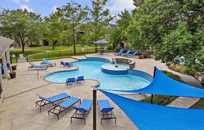 a resort style pool with blue umbrellas and chairs