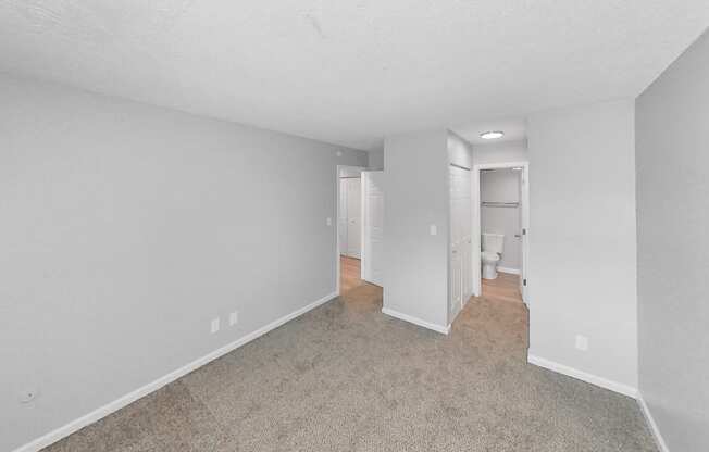 the living room of an apartment with white walls and carpet