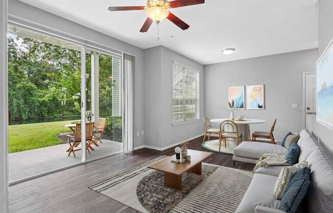 A living room with a ceiling fan and sliding glass doors.