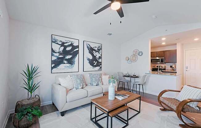 A living room with a white couch, a wooden coffee table, and a ceiling fan.