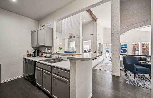 A modern kitchen with a large island and a blue chair in the living room.