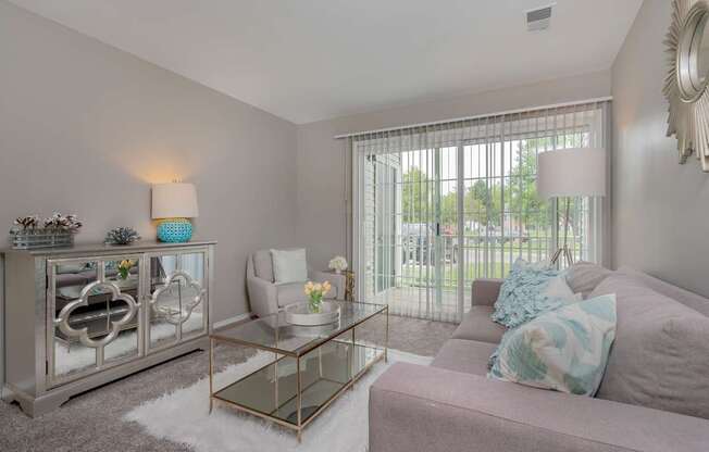 A living room with a grey couch, a glass coffee table, and a silver cabinet.
