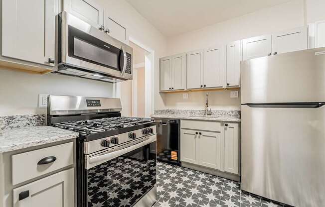 Updated kitchen with stainless steel appliances and a black and white floor.