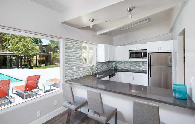 A kitchen with a pool outside the window.