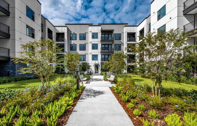 an exterior view of an apartment building with a sidewalk and landscaping at The Alibi at Lake Lilly, Ocoee, FL