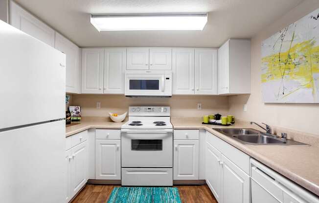 A kitchen with white cabinets and a white stove top oven.