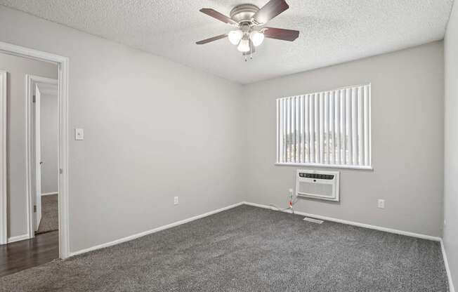 A room with a ceiling fan and a window with blinds.