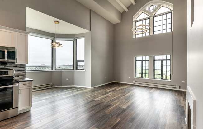 an empty living room with a kitchen and a large window