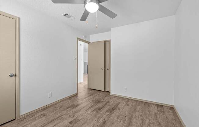 A room with a ceiling fan and wood flooring.