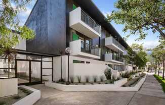 A modern building with a white and black exterior and a landscaped front yard.