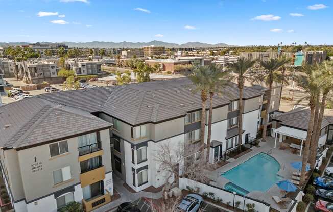 an aerial view of an apartment complex with a pool and palm trees