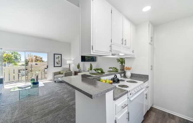 an open kitchen and living room with white cabinets and granite counter tops