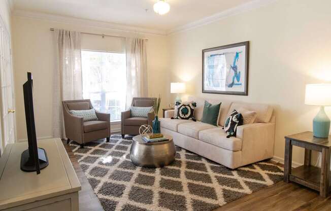 A living room with a couch, chairs, and a rug.