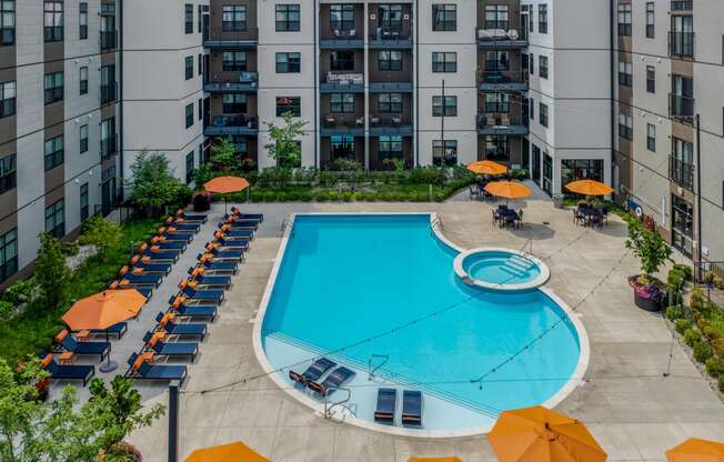 an aerial view of an apartment pool with umbrellas and lounge chairs around it
