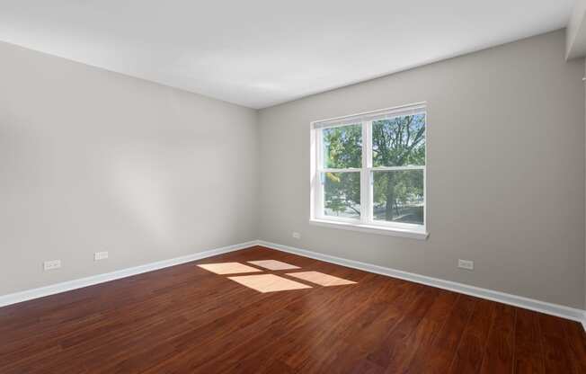 an empty room with wooden floors and a window