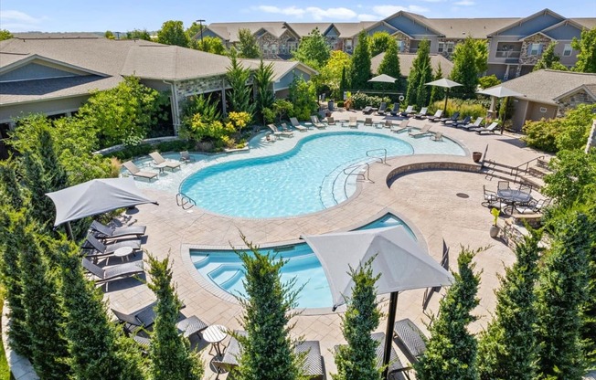 an aerial view of a resort style pool with chaise lounge chairs and umbrellas